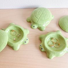 three green turtle shaped dishes with gold rings on their backs and one holding a wedding ring