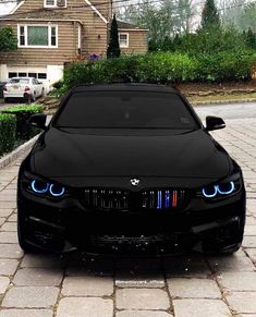 a black car with blue lights on it's hood parked in front of a house