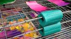 two rolls of toilet paper sitting on top of a metal rack filled with colorful paint