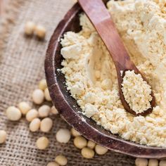 a wooden bowl filled with food next to some chickpeas and a spoon in it