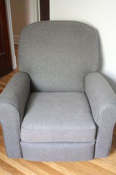 a gray chair sitting on top of a hard wood floor next to a doorway and door