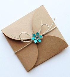 a brown envelope with a blue flower tied to the front, and some twine on top