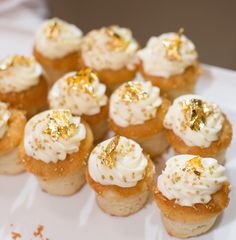 small cupcakes with white frosting and gold sprinkles on top