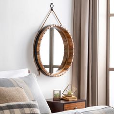 a round mirror hanging on the wall above a bed