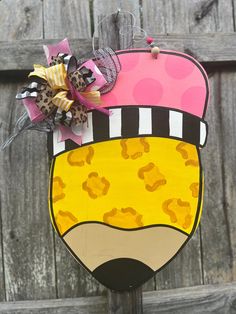 a wooden sign with a pink and yellow hat on it