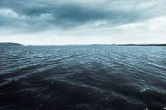 the water is very choppy and blue in this photo, with dark clouds above it