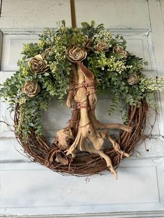 a wreath made out of branches and flowers hanging on a door frame with a cross in the middle