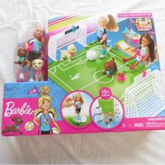 two barbie doll sets in their packaging on a white sheet covered bed with the contents