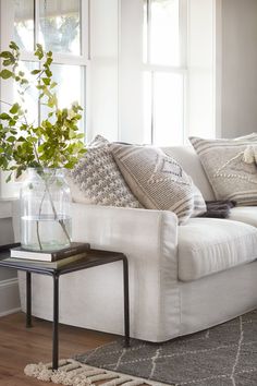 a living room with a white couch and some plants on the coffee table next to it