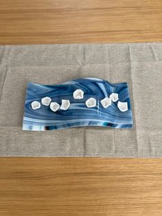 a blue and white glass plate sitting on top of a wooden table next to a gray place mat