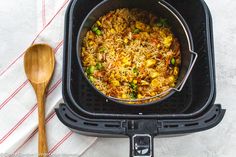 a pan filled with food sitting on top of a table next to a wooden spoon