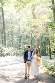 a man and woman walking down a path in the woods