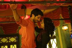 a man and woman dancing together in front of a red curtained room with lights