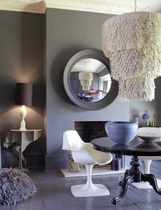 a dining room table with chairs and a round mirror