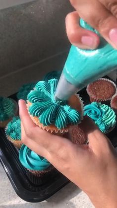 a person is decorating cupcakes with blue icing and green frosting