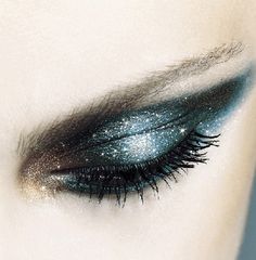 a woman's eye with blue and silver glitters on her eyeshade