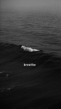 a black and white photo with the words breathe on it's left side in front of an ocean wave