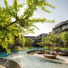 an outdoor seating area next to a pool with water running through it and trees in the background