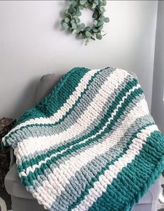 a green and white crocheted blanket sitting on top of a toilet next to a wreath