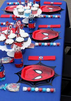 the table is set up with spiderman plates and cupcakes