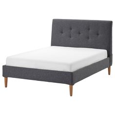 a bed with a gray upholstered headboard and white sheets on the bottom