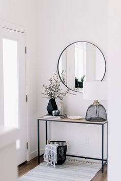 a black and white entryway with a round mirror on the wall next to a rug