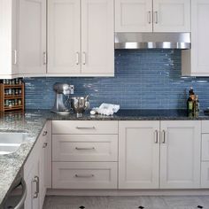 a kitchen with white cabinets and blue tile backsplash