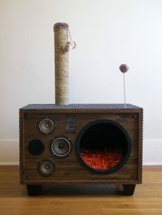 an old radio sitting on top of a wooden table next to a cat scratching post