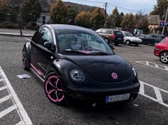 a black car with pink rims parked in a parking lot