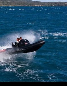 a man riding on the back of a boat in the ocean while being pulled by a boat