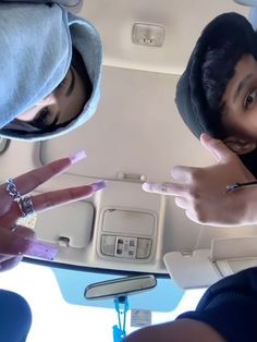 two people sitting in the back of an airplane with their fingers pointing at something on the ground