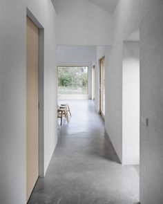 an empty hallway with wooden doors leading to another room that has white walls and concrete flooring