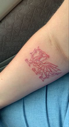 a woman's arm with a tattoo on it that has a red dragon on it