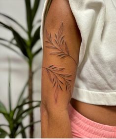 a woman's arm with a tattoo on it and a plant in the background