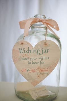 a glass jar with a wooden heart hanging from it's side and a tag attached to the lid