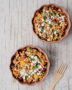 two bowls filled with food sitting on top of a wooden table next to a fork