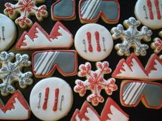 many decorated cookies are displayed on a black tablecloth with snowflakes and skis