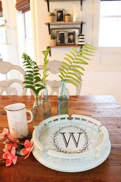 a wooden table topped with plates and vases filled with flowers on top of it