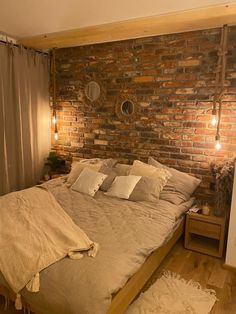 a bedroom with brick wall and wooden flooring, made up in beige linens