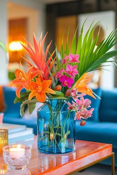 an arrangement of flowers in a blue vase on a table with candles and glassware