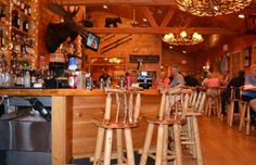 people sitting at tables in a restaurant with wooden bar stools