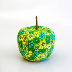 an apple painted with flowers and leaves is shown on a white surface, ready to be used as a decoration