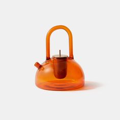 an orange tea kettle sitting on top of a white table