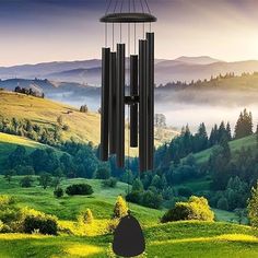 a wind chime hanging from the side of a hill with mountains in the background