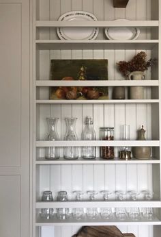 a white shelf filled with lots of glassware and dishes on top of wooden shelves