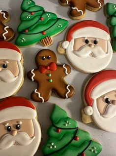 christmas cookies decorated with santa claus and gingerbreads are on a white tablecloth