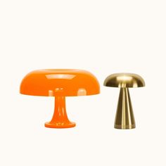 two orange and gold lamps sitting next to each other on a white surface with one lamp turned upside down