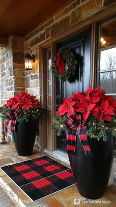 two large black vases with red poinsettias on the front porch for christmas