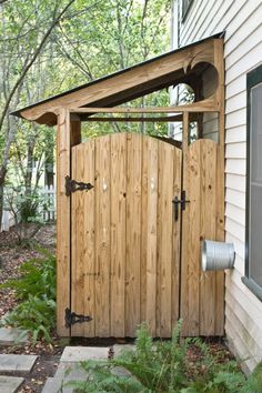 an outside view of a house with a wooden gate and potted plants in the yard