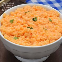 a white bowl filled with macaroni and cheese on top of a wooden table